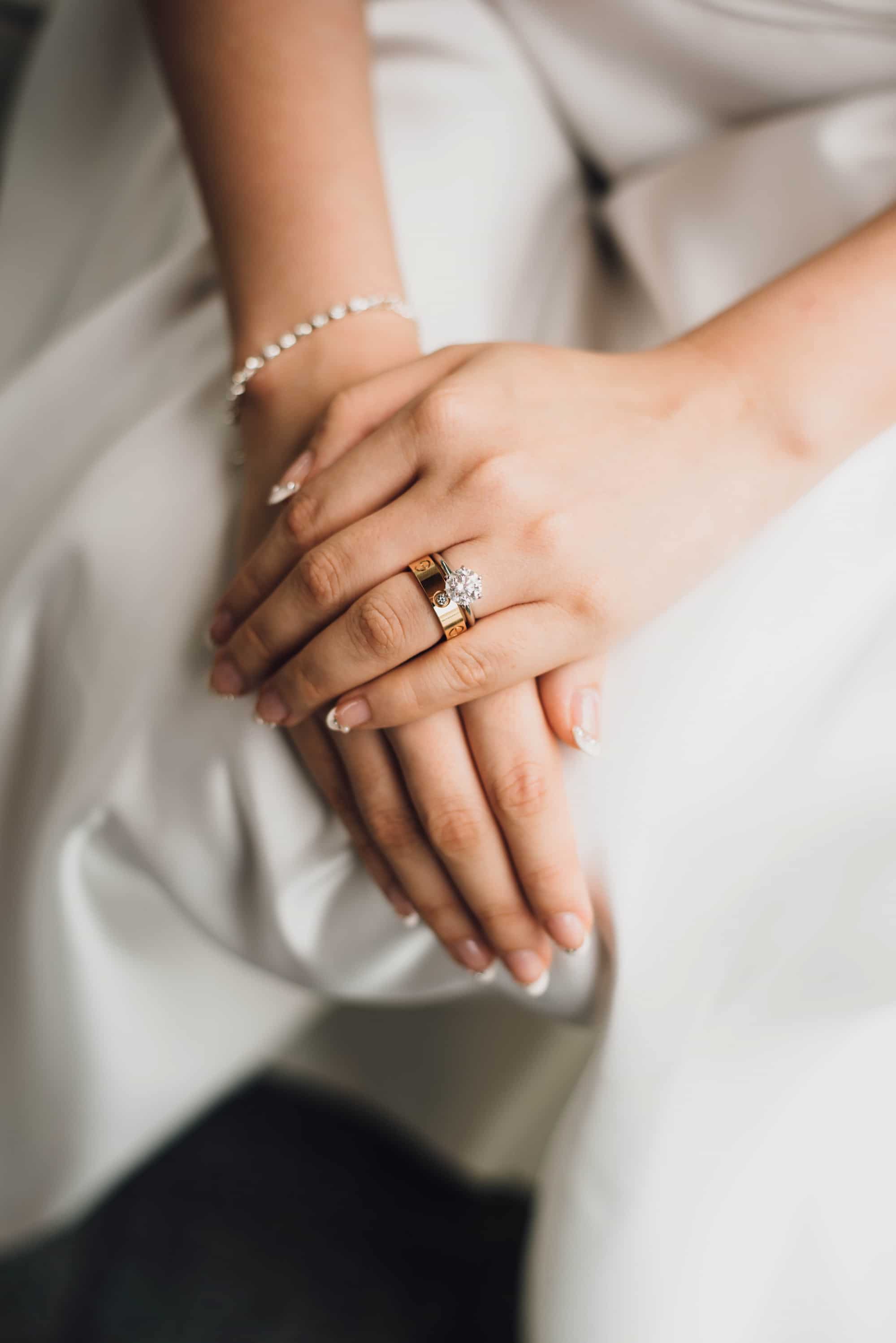Im Schoß gefaltete Frauenhände mit Verlobungs- und Ehering